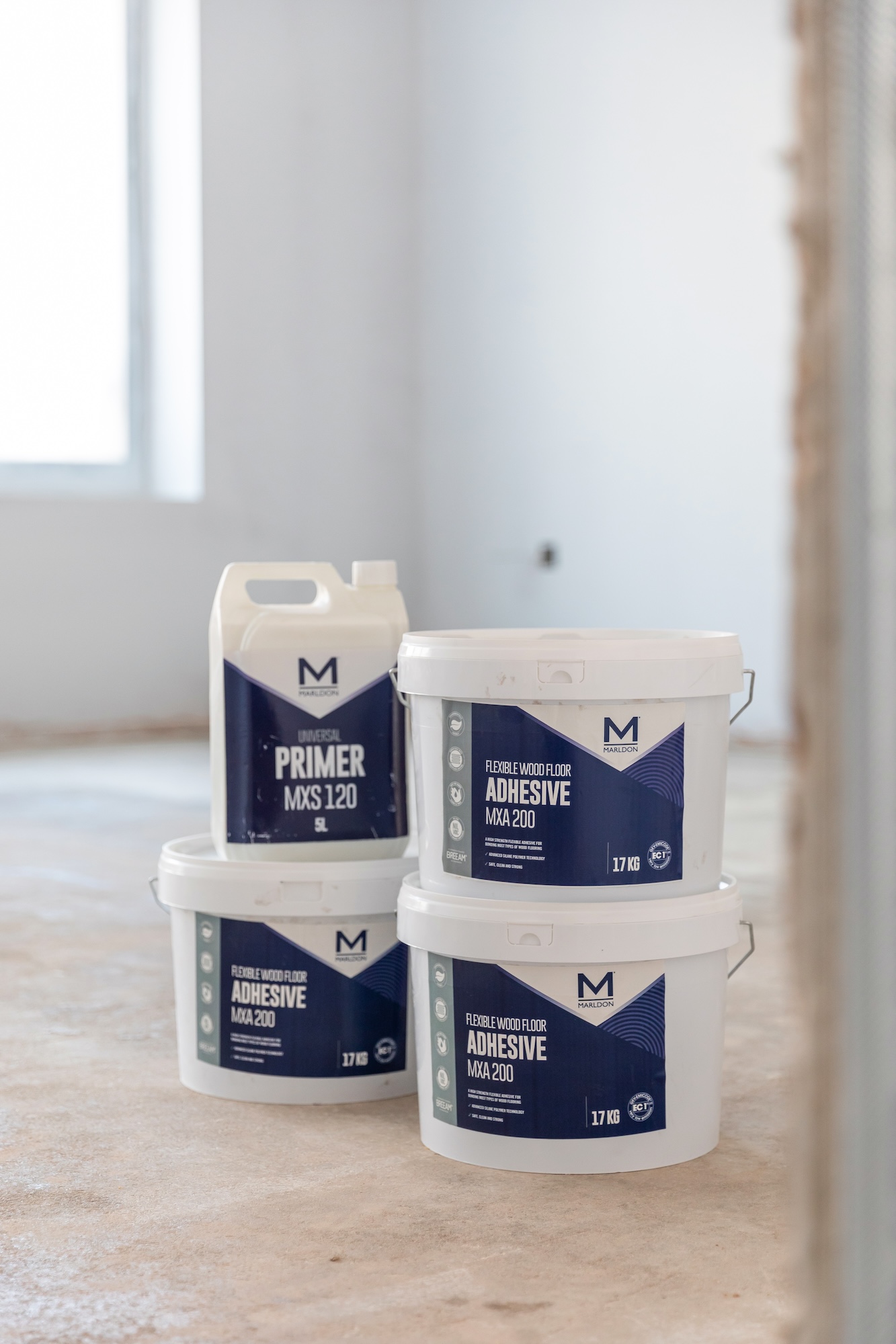 3 tubs of Marldon MXA200 Flexible Wood Floor Adhesive stacked up with 1 bottle of Marldon MXS120 Universal Primer on the top