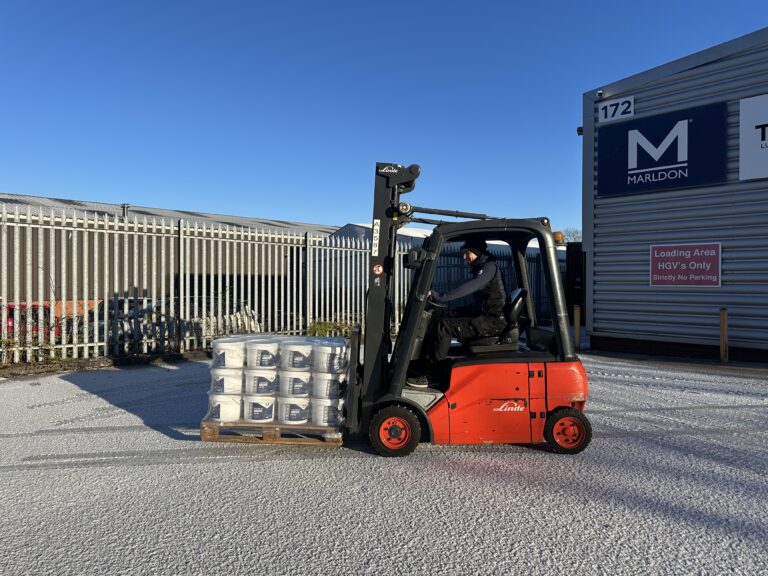 Red Linde forklift loading palletted goods at industrial warehouse