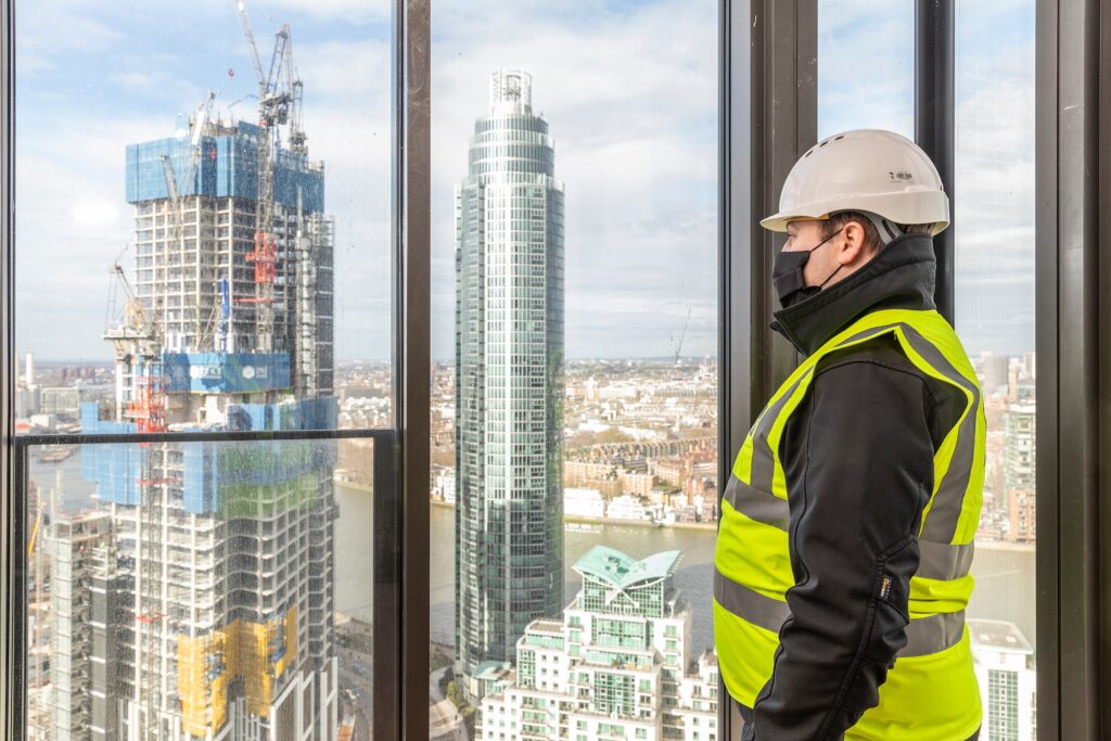 Construction worker surveying cityscape from high-rise window